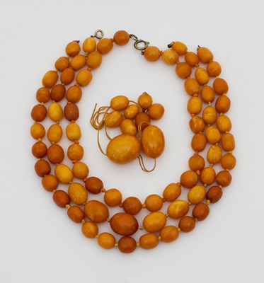 Lot 555 - Three matching amber bead necklaces, graduated...