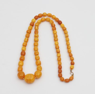 Lot 571 - An amber bead necklace, graduated with oval...