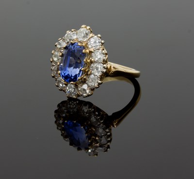 Lot 615 - A sapphire and diamond cluster ring, claw set...