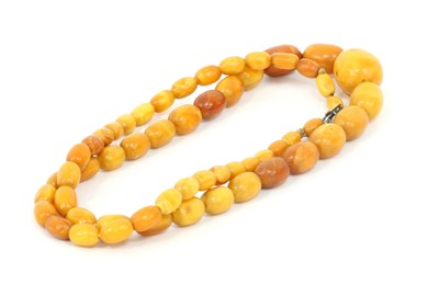 Lot 1203 - A single-row amber bead necklace graduated...