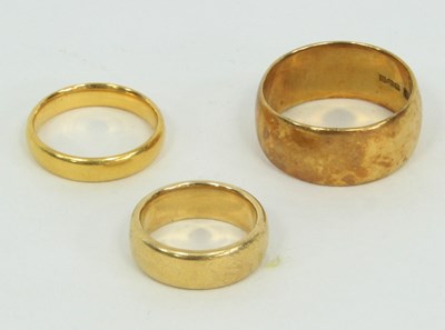 Lot 1231 - Three gold wedding bands, two 18ct gold, total...