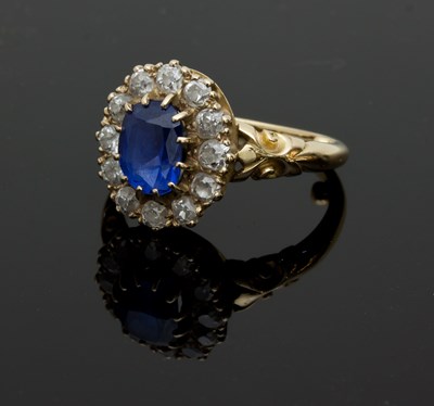 Lot 1297 - A sapphire and diamond cluster ring, claw set...