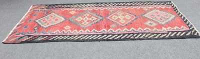 Lot 566 - A kelim runner with four medallions on a red...