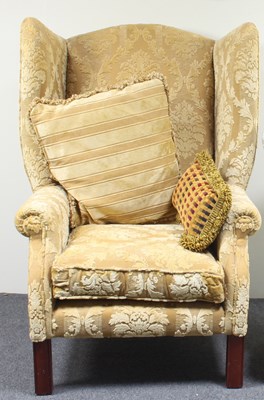 Lot 706 - A wing back armchair covered in gold brocade...