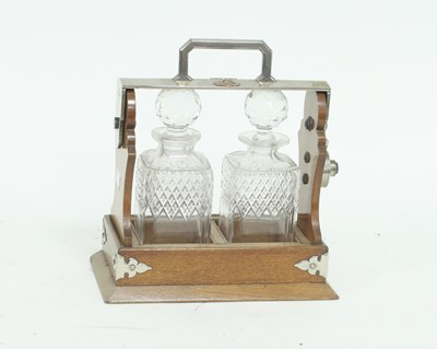 Lot 887 - A two-decanter oak tantalus, crested and...