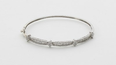 Lot 436 - A diamond set hinged bangle, set with three...