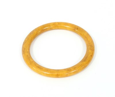 Lot 234 - A butterscotch coloured bangle, 8.5cm diameter,...