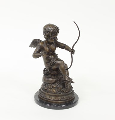 Lot 519 - A bronze figure of Cupid, seated on a...