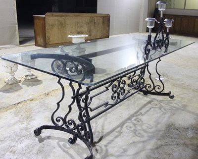 Lot 700 - A large glass top table with a wrought iron...