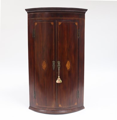 Lot 930 - A George III mahogany bowfront corner cupboard,...