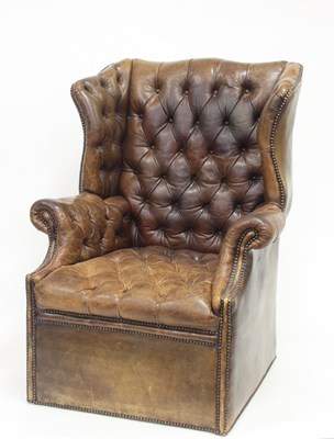 Lot 1002 - A brown leather button back wing armchair with...