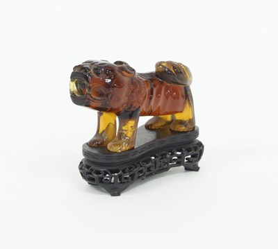 Lot 420 - A Chinese amber coloured carved lion on a...