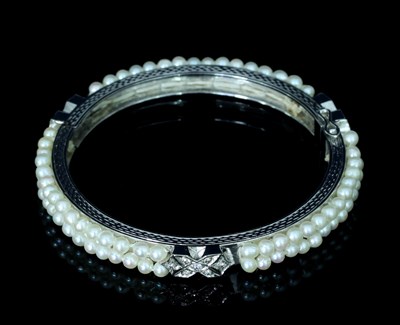 Lot 136 - A diamond and pearl bangle, of hinged form,...