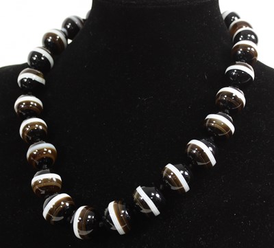 Lot 555 - A banded agate necklace of twenty-six large...