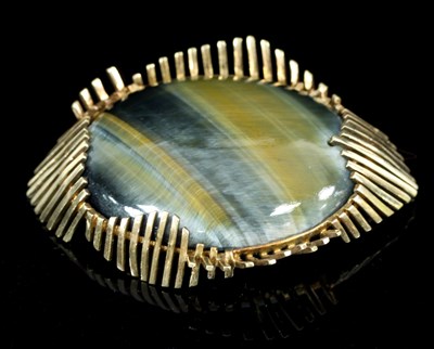 Lot 586 - A 1960s tigers eye brooch, of oval form framed...