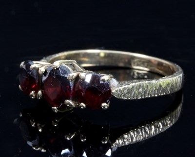 Lot 463 - A garnet three-stone dress ring to a 9ct gold...