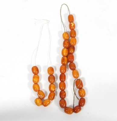 Lot 444 - A quantity of oval amber beads, thirty-two in...