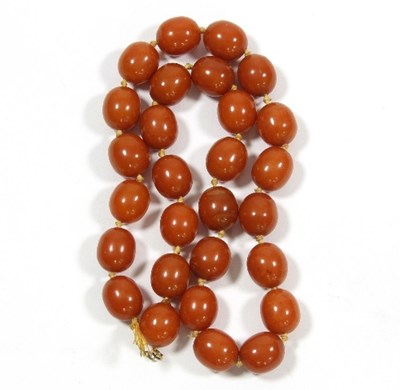 Lot 447 - A single row of oval amber beads, twenty-eight...