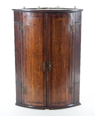 Lot 680 - A mahogany bow-fronted corner cabinet, banded...