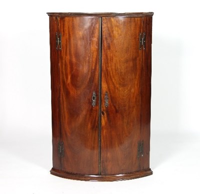 Lot 675 - A mahogany bowfront hanging corner cupboard,...