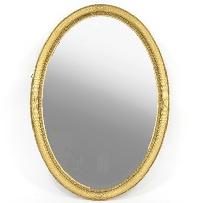 Lot 681 - An oval wall mirror in a gilded and reeded...