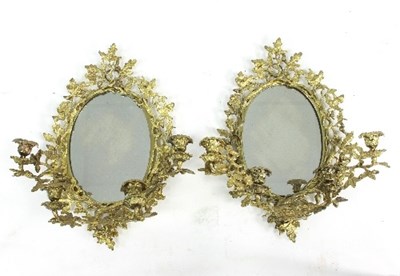 Lot 682 - A pair of oval mirrors with gilt metal foliate...