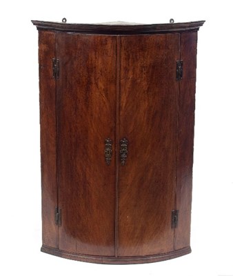 Lot 720 - A George III mahogany bowfront corner cupboard,...