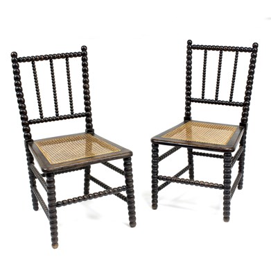 Lot 676 - A pair of ebonised single chairs with cane...