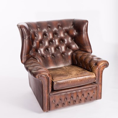 Lot 502 - A brown leather button back wing armchair with...