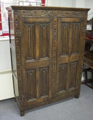 Lot 579 - A carved oak cupboard, enclosed by two...