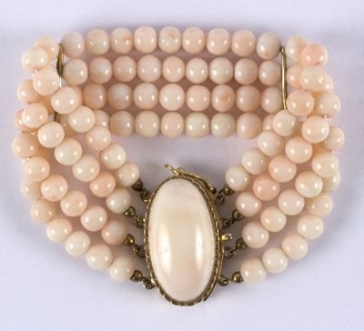 Lot 24 - A three-row pink coral bead bracelet with an...