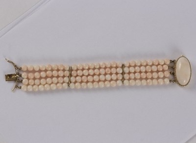 Lot 24 - A three-row pink coral bead bracelet with an...