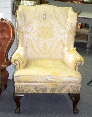 Lot 896 - A mahogany framed wing armchair with cream...