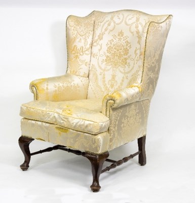 Lot 1027 - An upholstered wingback armchair on short...