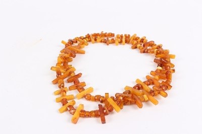 Lot 181 - A single row beaded amber necklace with oblong...