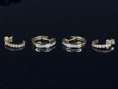 Lot 559 - A pair of diamond channel set ear hoops, each...