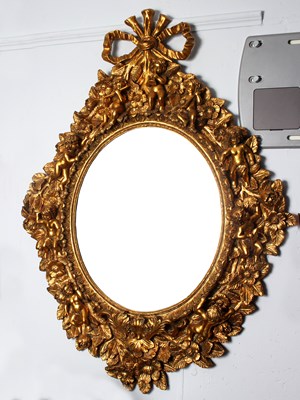 Lot 791 - An oval wall mirror in a gilded frame...