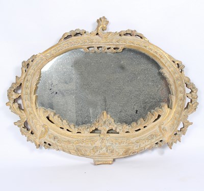 Lot 678 - An oval wall mirror in a carved gilded and...