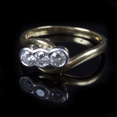 Lot 189 - A three-stone diamond ring, in a crossover...