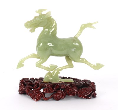 Lot 378 - A jade carving of a galloping horse, on a...