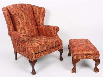 Lot 933 - An upholstered wingback armchair, covered in...