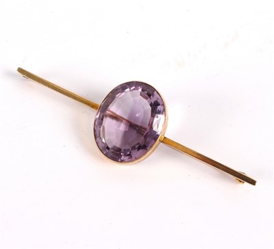 Lot 12 - An amethyst bar brooch, the large oval stone...