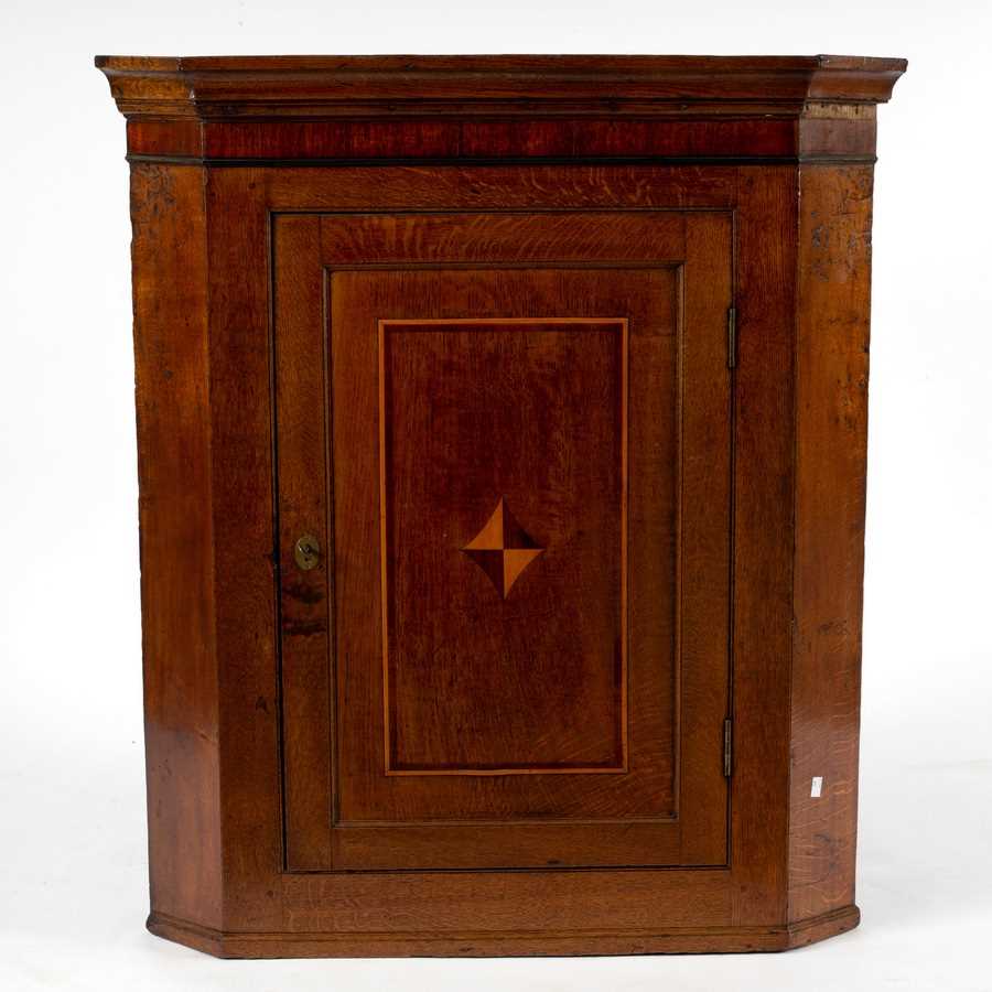 Lot 60 - An oak corner cupboard, the panelled door...