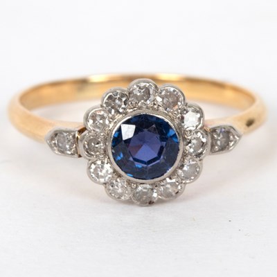 Lot 713 - A sapphire and diamond cluster ring flanked by...