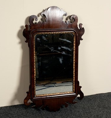 Lot 611 - A small mahogany wall mirror with carved ear...