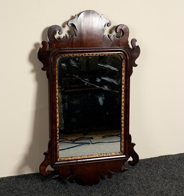 Lot 580 - A small mahogany wall mirror with carved ear...