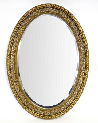 Lot 653 - An oval wall mirror in decorative plaster gilt...