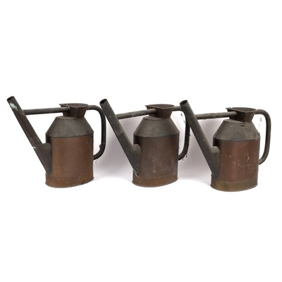 Lot 582 - Three copper watering cans, 42cm high