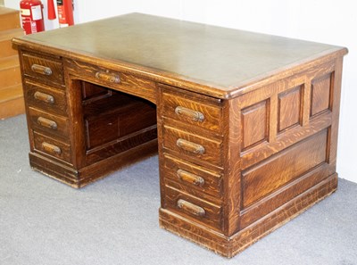 Lot 855 - An oak pedestal desk fitted nine drawers...