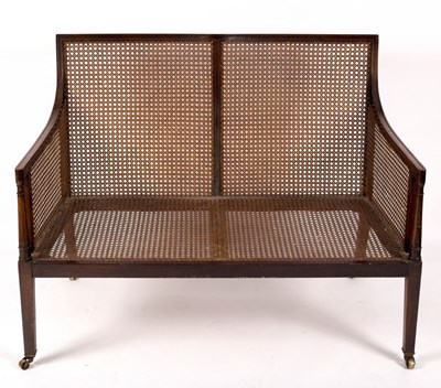 Lot 1138 - A Regency style bergère two-seat sofa, with...